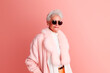 © BUDDHA - Happy and funny cool old lady with fashionable clothes portrait on pink background - grandmother with extravagant style, concepts about lifestyle, seniority and elderly people. Generative Ai