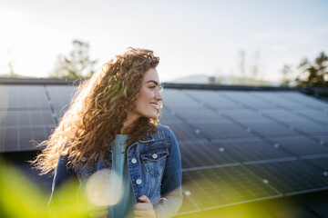 Portrait of young woman on roof with solar panels.