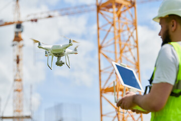 Wall Mural - drone operated by safety engineering inspector. construction worker piloting drone on building site