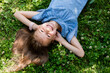happy little girl lying on the green grass in summer top view