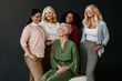 © gstockstudio - Multi-ethnic group of confident mature women bonding and smiling against black background