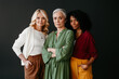 © gstockstudio - Three confident mature women looking at camera while bonding against grey background