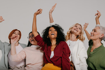 Wall Mural - Group of happy mature women gesturing and smiling against grey background