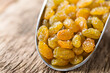 Golden seedless sultana raisins in metal scoop on wood (Selective Focus, Focus on the front of several raisins in the front)