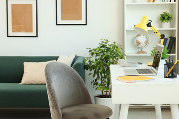 Poster - Cozy workspace with modern laptop on white wooden desk and comfortable chair at home