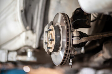 Poster - Disc brake of the vehicle for repair, in process of new tire replacement. Car brake repairing in garage.Suspension of car for maintenance brakes and shock absorber systems. Replacement of brake pads.