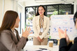 © bongkarn - A female marketing assistant presented her new campaign to her team in the meeting.