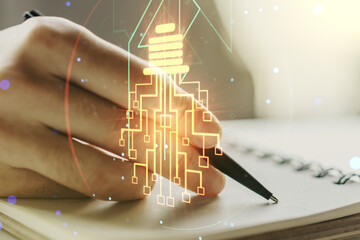 Poster - Creative light bulb with chip hologram and man hand writing in notepad on background, artificial Intelligence and neural networks concept. Multiexposure