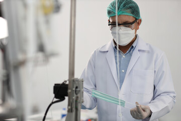 Canvas Print - Worker in personal protective equipment or PPE inspecting quality of mask and medical face mask production line in factory, manufacturing industry and fac