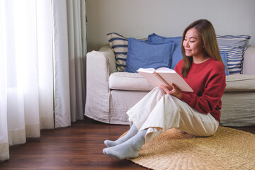 Wall Mural - Portrait image of a young woman reading a book at home