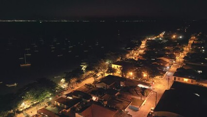 Wall Mural - Aerial view of the coastal town of Santo Antonio de Lisboa in Brazil during night time. Footage has high level of noise