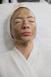 © RomArt production - Woman rests in a beauty clinic, sporting a green facial mask aimed at rejuvenating improving skin. Active cleansing lifting treatment effectively combat acne reduce the appearance of enlarged pores.