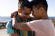 © Wavebreak Media - Happy biracial gay male couple smiling and embracing by the sea