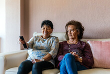 Two Older Modern Women Watching Tv Sitting On The Sofa
