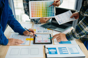 UX developer and ui designer brainstorming about mobile app interface wireframe design with customer breif and color code at modern office..