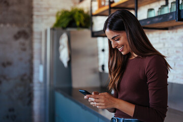 portrait of young woman smiling while using smartphone.
