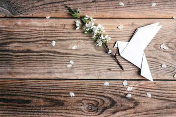 Wall Mural - Paper origami dove of peace with apple blossom branch on old wooden background.