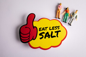 Eat Less Salt. Sticky note with text and miniature human figures on a white background