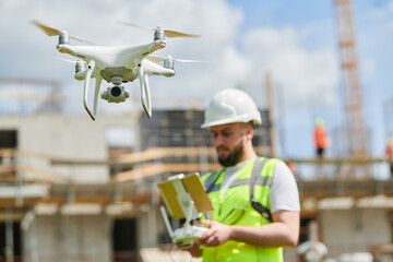 Wall Mural - drone operated by safety engineering inspector. construction worker piloting drone on building site