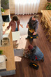 © pressmaster - Above view of two repairmen in workwear checking pipes in the kitchen while one of them communicating with troubled housewife