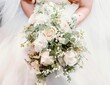 Wedding bouquet with white roses, eucalyptus leaves, and Baby's breath flowers in the bride's hands