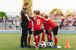 Happy Soccer Kids With Coach Standing in a Circle. Children in Football Team Gathering With Trainer During Tournament Match Time Break