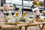 Fototapeta Kawa jest smaczna - Wooden table with alcoholic drinks and different food in outdoor cafe