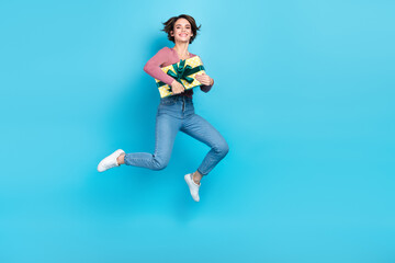 Sticker - Full body photo of carefree energetic lady hands hold giftbox jumping empty space isolated on blue color background