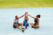 © Emil Lime/peopleimages.com - Happy people, team and high five on stadium track for running, workout or exercise together in partnership. Sports group touching hands in support, fitness or friends in motivation, unity or training
