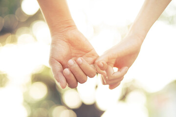 Wall Mural - Couple lovers romantic holding hands towards with bright sun flare in public parks, or close up view in a conceptual image first love adolescent young relationship. lover