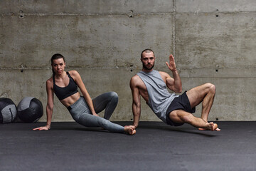 An attractive couple in the gym engaging in various stretching exercises together, showcasing their dedication to fitness, flexibility, and overall well-being. With synchronized movements, they