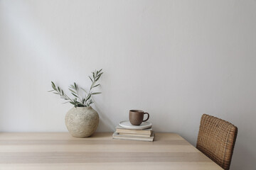 neutral mediterranean home design. vintage vase with olive tree branches, cup of coffee. books on wo