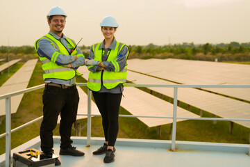 engineers man and woman standing at solar farm or photovoltaic cell construction. Industrial Renewable energy of green power. factory worker working on solar farm.