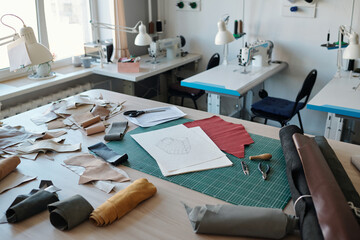 Poster - Workplace of tanner with sketches on papers, rolled leather textile, handtools and pieces of fabric against desks with sewing equipment