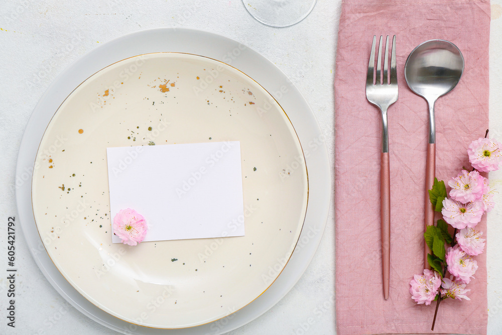 Beautiful table serving with cutlery, blooming tree branch and blank invitation card white background