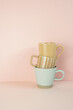 Stack of brown and mint blue mug cups on pink table. pink wall background. copy space