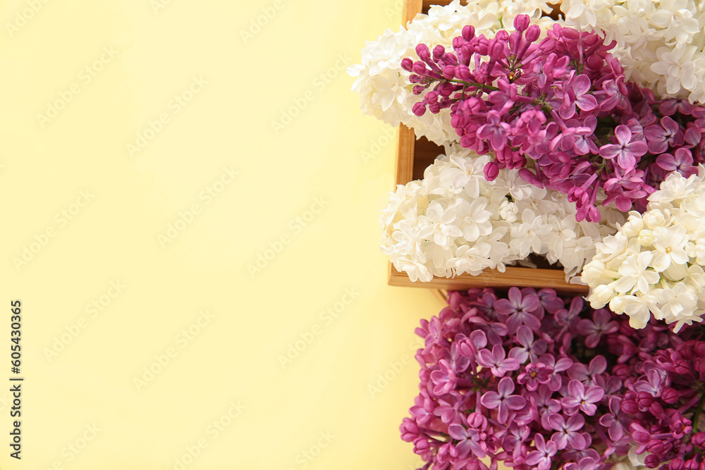 Wooden boxes with beautiful lilac flowers on pale yellow background