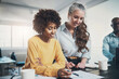 © Flamingo Images - Diverse businesswomen smiling while reading through paperwork together in an office