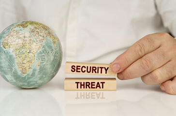 Poster - There is a globe on a white reflective surface, in the hands of wooden blocks with the inscription - Security threat