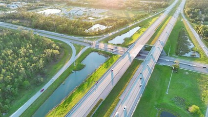 Poster - Aerial view of freeway overpass junction with fast moving traffic cars and trucks in american rural area at sunset. Interstate transportation infrastructure in USA