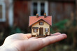 Photo of a person holding a small house in their hand for real estate purposes