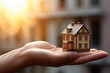 Photo of a person holding a small model house, symbolizing real estate investment