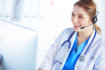 Doctor wearing headset sitting behind a desk with laptop