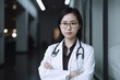 young asian female doctor in a hospital at night, portrait of a professional woman posing with crossed arms and a stethoscope, successful lady generative AI