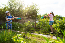 Two Little Kids Playing With Water Guns On Hot Summer Day. Funny Summer Games For Kids. Family Having Water Fight Outdoors