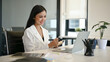 © bongkarn - Confident Asian businesswoman focuses on her work on laptop, working at her desk