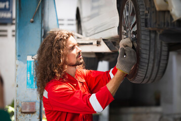 Technician man working in auto service with lifted vehicle, Auto mechanic working in garage, Car repair and maintenance