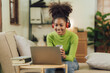 © Kritdanai - Focused young African female college student working on a laptop on living room.