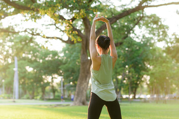 female jogger. fit young asian woman with green sportswear stretching muscle in park before running 