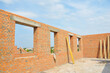 Unfinished brick house construction with windows, concrete lintels and no roof.